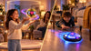 Child playing with a Flyokay MemoOrb flying orb ball beside a floor-gliding hover ball in a side-by-side comparison scene
