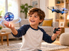 Child comparing a Flyokay MemoOrb flying orb ball with a small remote-control drone in a living room