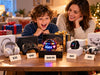 Parent and child comparing tech gifts at different prices, including a Flyokay MemoOrb priced at $49.99, headphones, a game controller, smartwatch, and drone