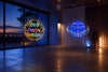 Flyokay MemoOrb displaying a personalized Happy Birthday LED message beside a regular flying orb with colorful light trails